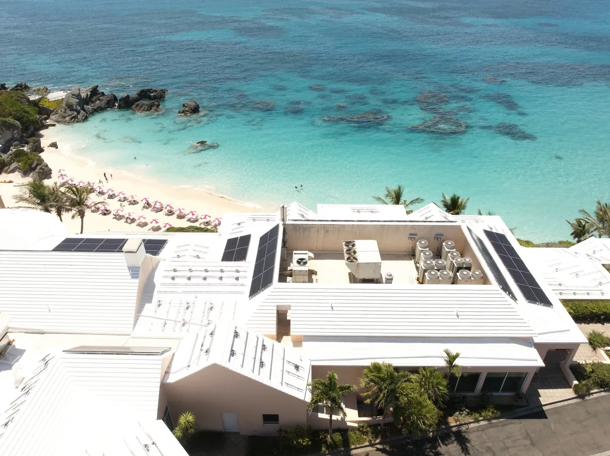 Commercial roofs above a Bermuda beach, restored by AES RoofTech, with solar panels back on