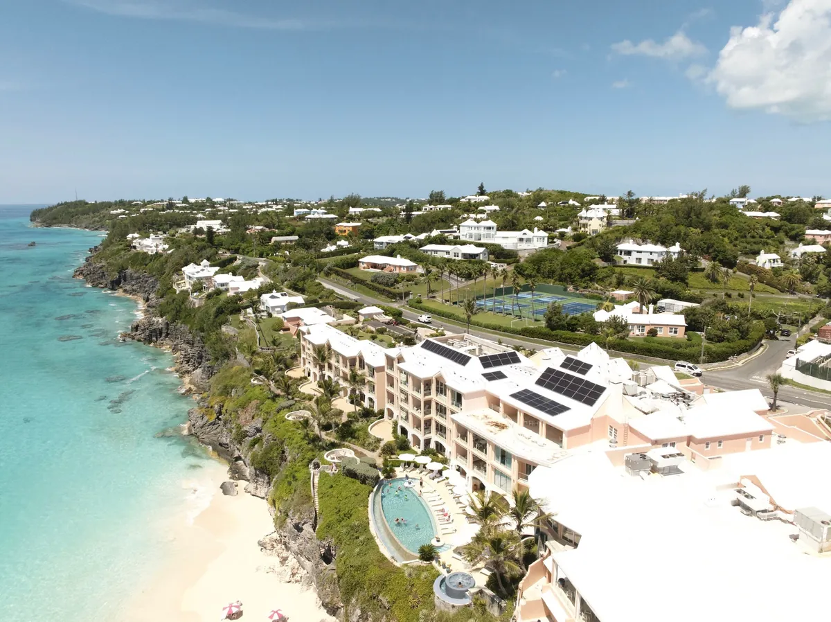 A resort on the south shore of Bermuda with restored white roofs and solar panels, seen from the air