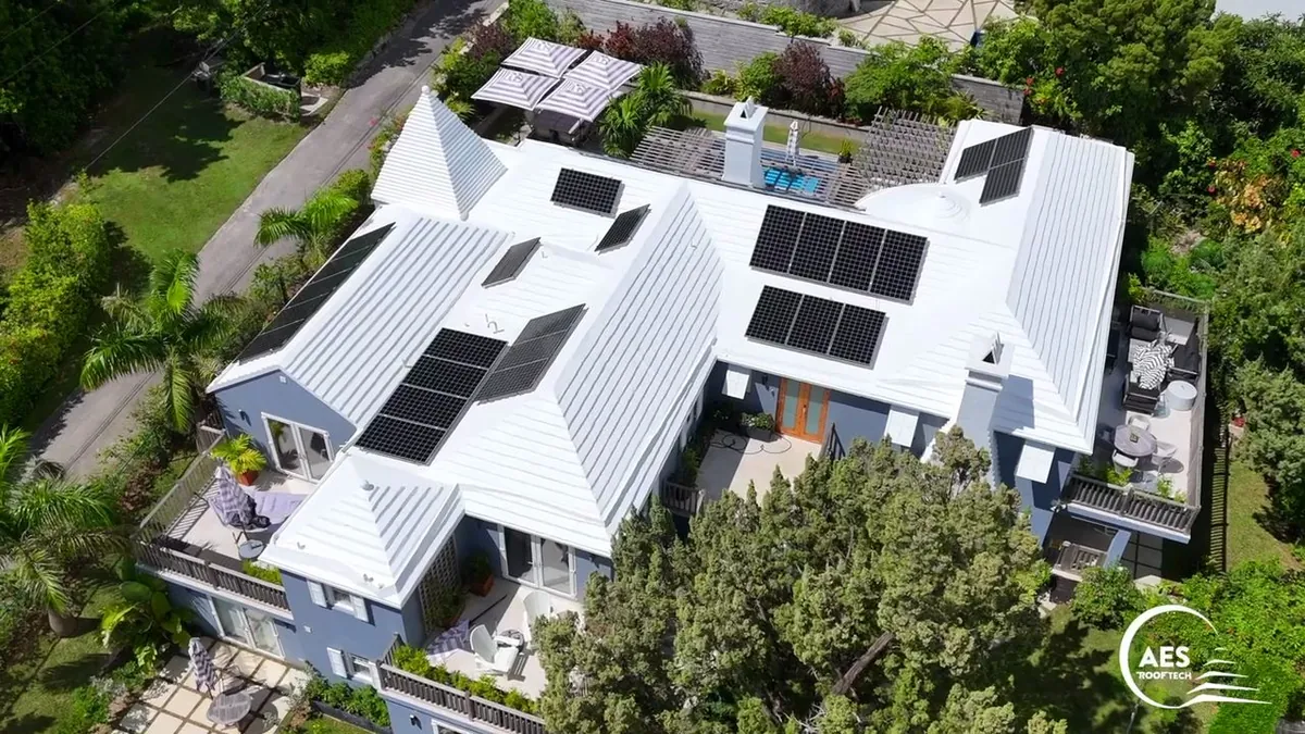 A Bermuda home with its solar panels back on a freshly restored white roof, seen from the air